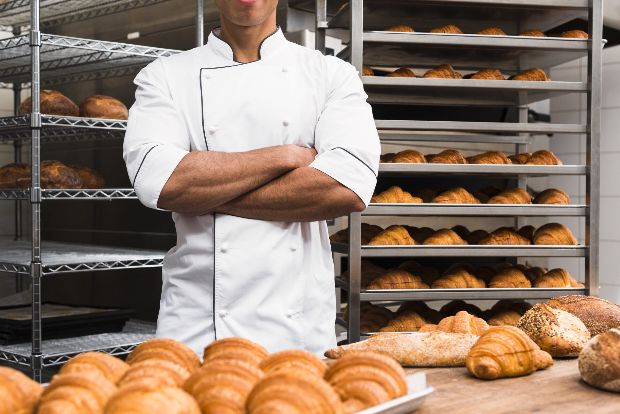 midsection-male-baker-with-his-arms-crossed-standing-bakery